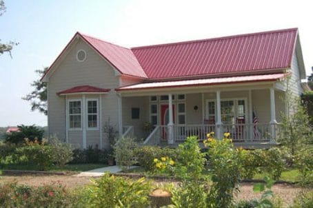 A Red Metal Roof With Tan Siding